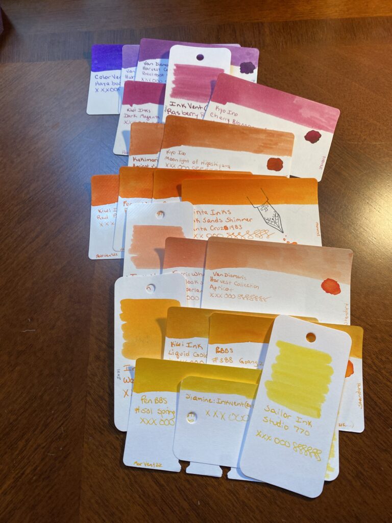 Sample cards still laid out in rows by color grouping, with new group colors overlapping them from top to bottom. 3 purples, 3 magentas, 2 darker oranges, 4 medium/bright oranges, 3 peach oranges, 3 orange/yellows, 3 yellows. 
