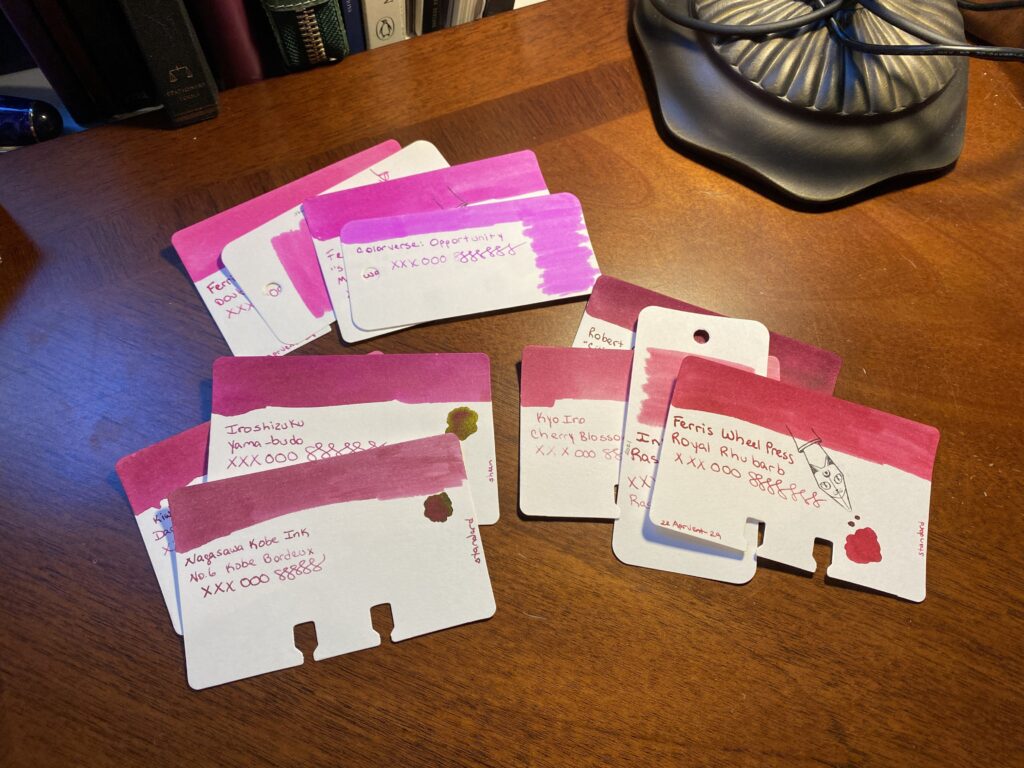 The larger pile of magenta sample cards have been separated out into smaller piles, grouped by tone. There are only three piles, one is more neon pink, another sort of a rosey pink magenta, and then the last one is a magenta that leans into the red tones. 