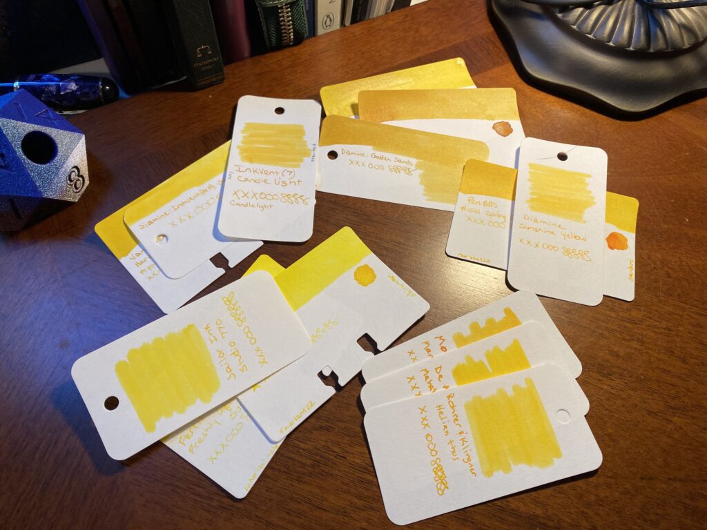 The larger pile of yellow sample cards have been separated out into smaller piles, grouped by tone. They range from a very vivid yellow to darker ranges with touches of gold or orange. 