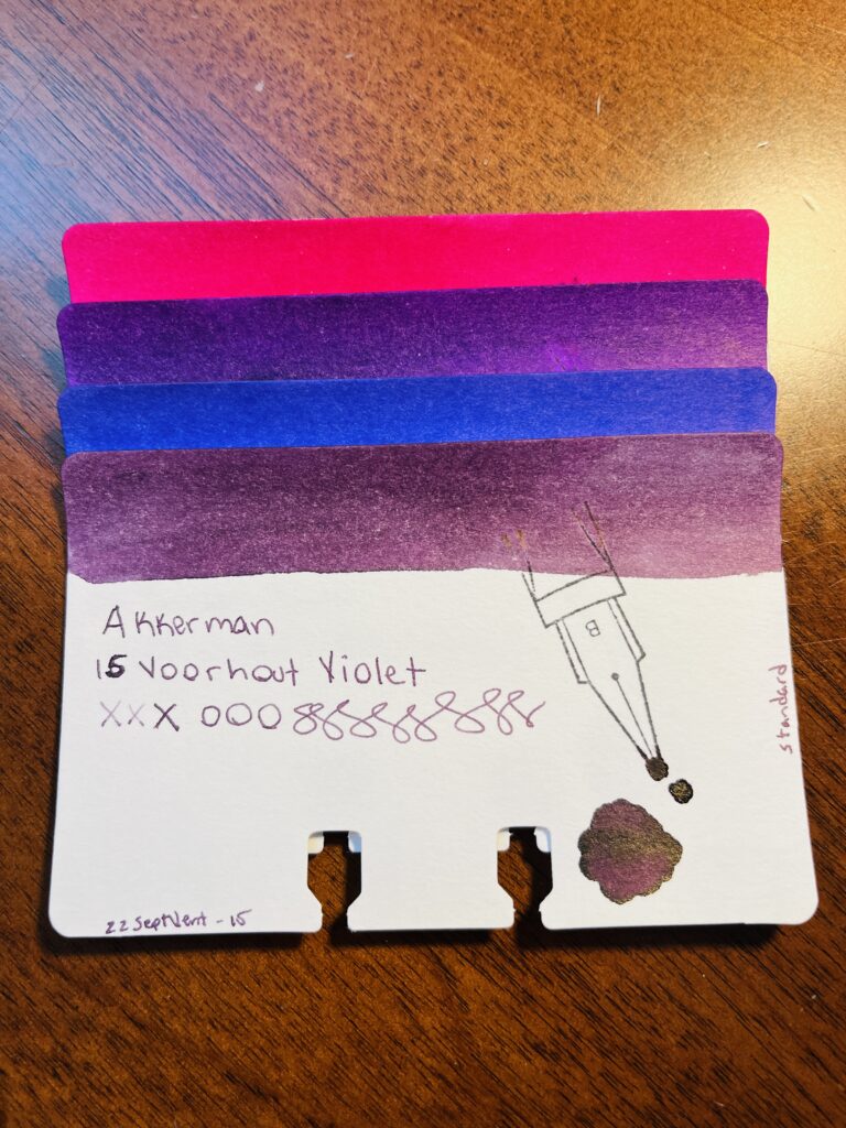 4 sample cards of different purples stacked on top of each other, only the color band at the top is visible on 3 of the cards. The last one is fully visible. It reads “Akkerman 15 Voorhout Violet, xxxooosssssss, 22SeptVent-15, standard” There is a stamp of a nib with a B on it, and a pool of the color used on the card. 