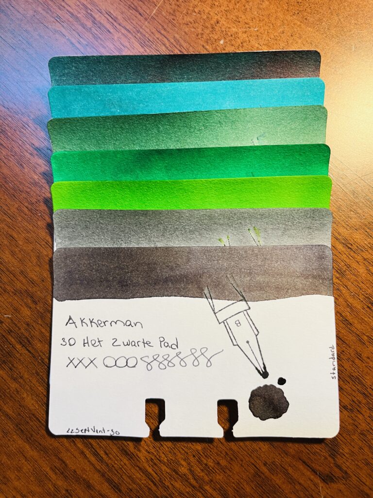 7 sample cards of different greens and greys stacked on top of each other, only the color band at the top is visible on 6 of the cards. The last one is fully visible. It reads “Akkerman 30 Het Swarte Pad, xxxooosssssss, 22SeptVent-30, standard” There is a stamp of a nib with a B on it, and a pool of the color used on the card. 