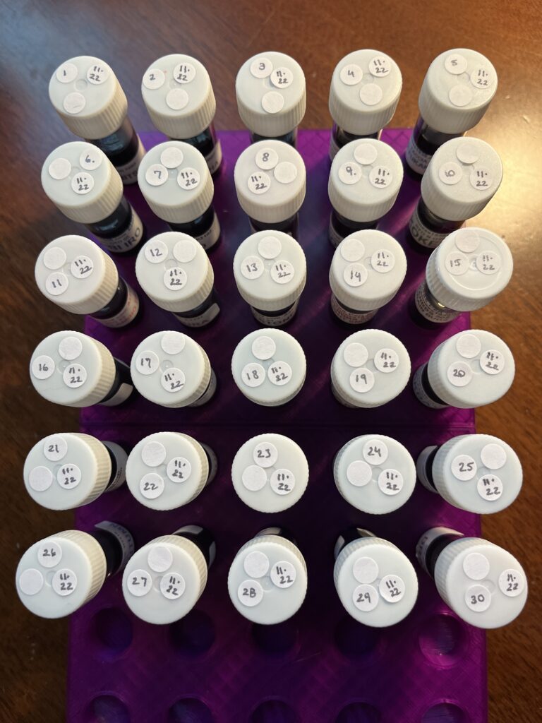 30 ink vials from top down, the caps are all white, and they have round white stickers with the date. 