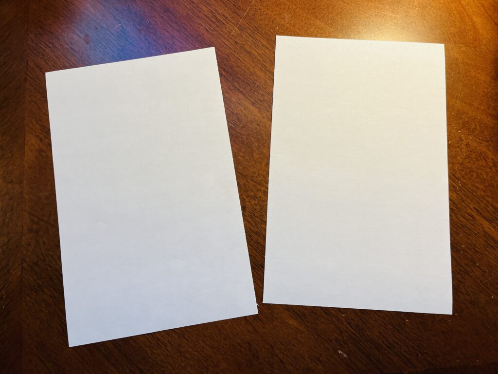 Two halves of an 8.5 x 11” piece of white computer paper. 