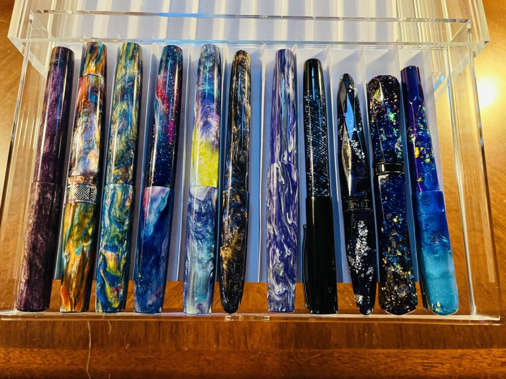 Top down of a variety of pens with paper separators. The edges of the dividers are visible, but not intrusive, and the pens are cleanly separated. 