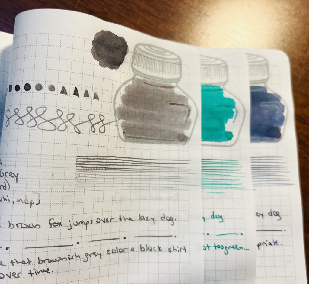 The edges of three pages in a journal. Each page has samples of a single ink, a grey, a bright green, and a dark blue. Only the edges of the ink bottle mark and the lines drawn are visible on two of the pages. The top page you can see the geometric shapes, ink pool, ink bottle color in, straight lines, the end of the phrase “the quick brown fox jumps over the last dog” then a page separator of a straight line followed by a dot repeated, and then thoughts on the ink.