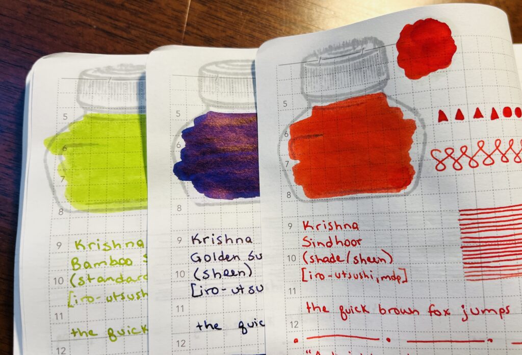 The edges of three pages in a journal. Each page has samples of a single ink, a bright green, dark blue, and a bright red. Only the edges of the ink bottle mark and the lines drawn are visible on two of the pages. The top page you can see the geometric shapes, ink pool, ink bottle color in, straight lines, the end of the phrase “the quick brown fox jumps over the last dog” then a page separator of a straight line followed by a dot repeated, and then thoughts on the ink.