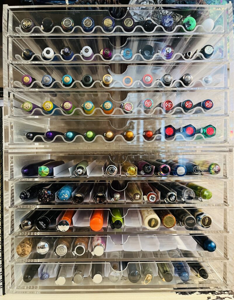 All 10 clear acrylic drawers, filled with various pens. The top five drawers have the curved clear acrylic dividers. The bottom 5 drawers have the squared off paper dividers.