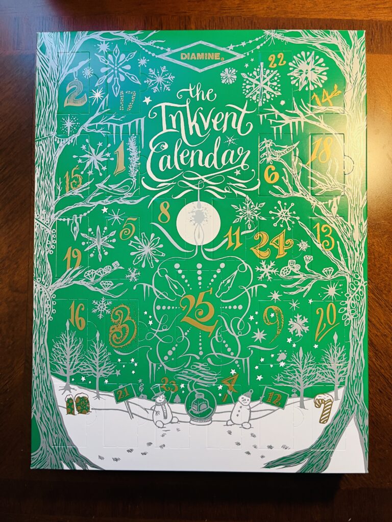 The 2022 Diamine Inkvent calendar, which is a green box with a snow scene in white, and numbered doors in gold. 