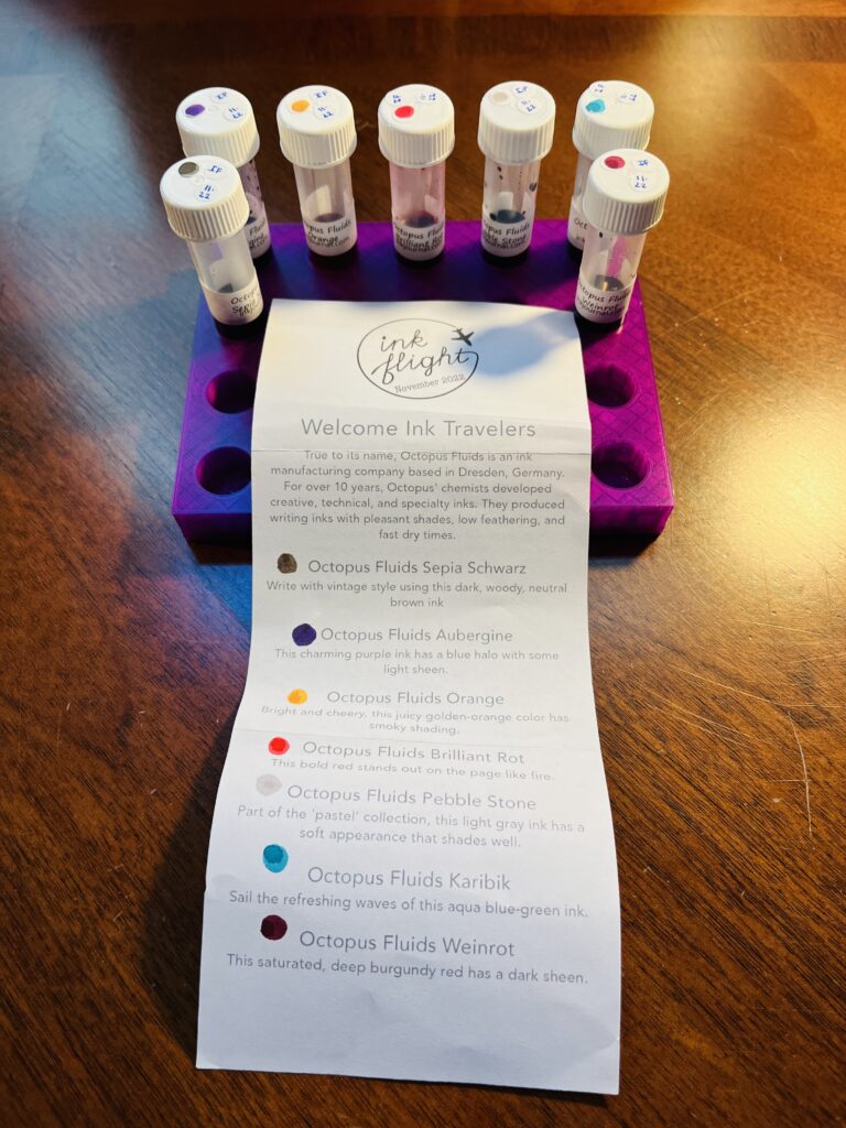 A purple tray with 5 inks lined up side by side and 1 more on either side. There is a long piece of paper with a lot of printed text and a dot of ink color next to each paragraph describing the ink. Those descriptions will be included in the listed inks under the following photos. 