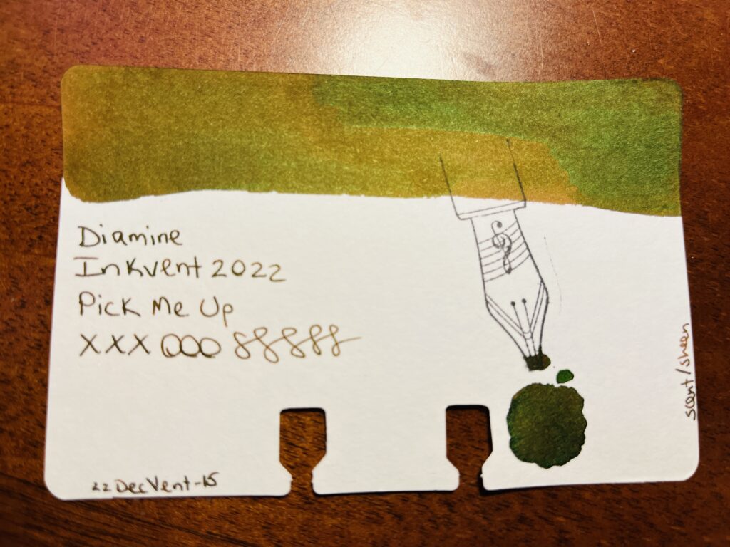Sample card with a long swatch of color at the top, and a stamp of a nib on the right side. There is text reading “ Diamine, Inkvent 2022, Pick Me Up, xxxooosssss, 22DecVent-15, scent/sheen”